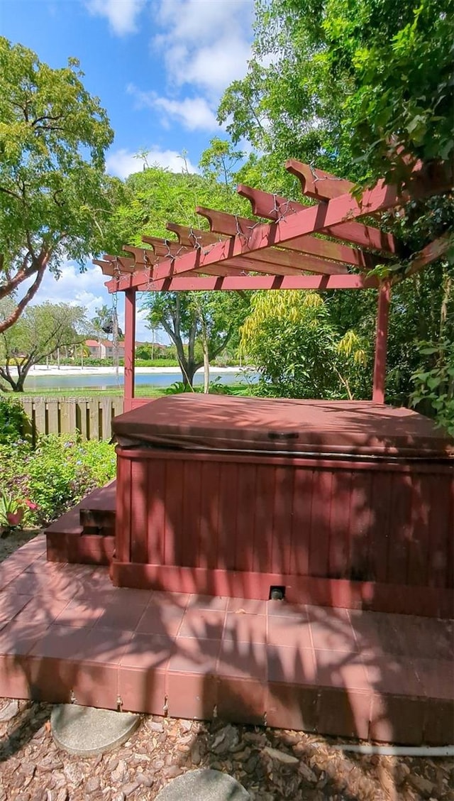 exterior space with a pergola, a water view, and a hot tub