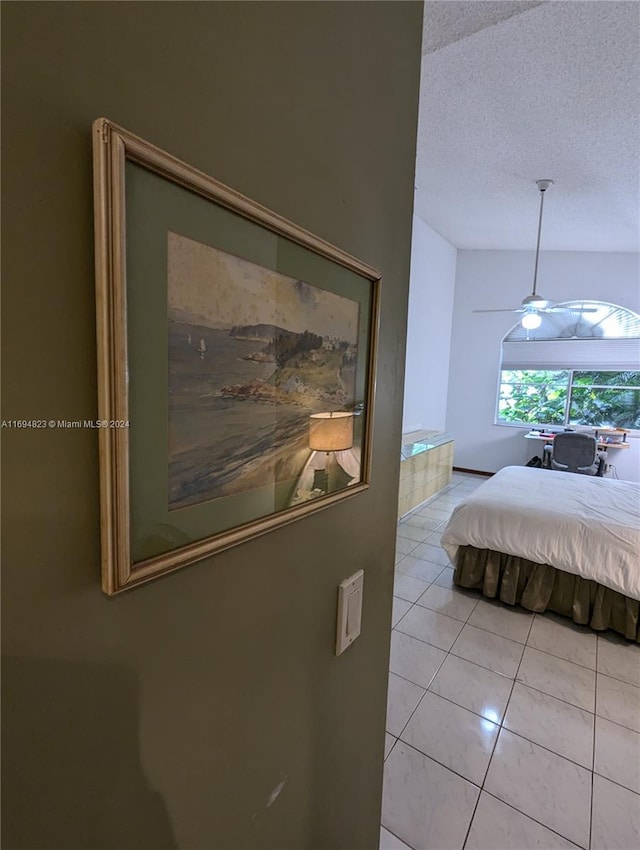 bedroom with ceiling fan, light tile patterned floors, and a textured ceiling