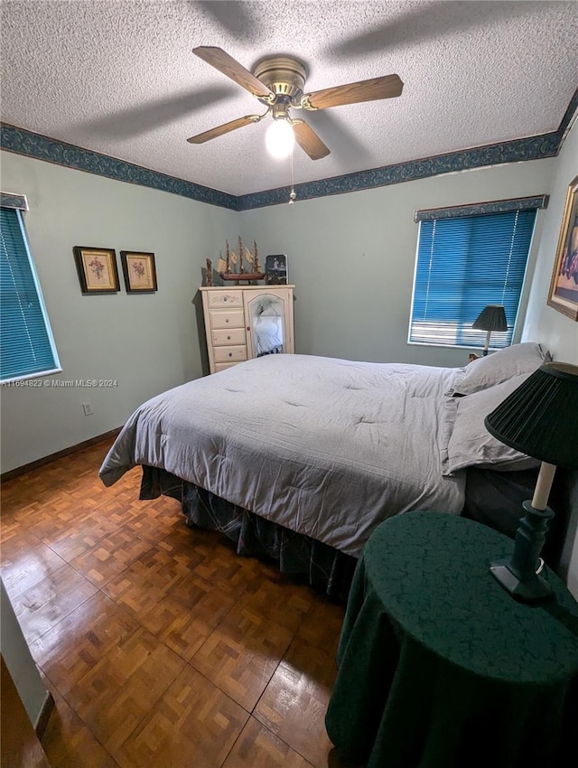 bedroom featuring a textured ceiling, ceiling fan, and dark parquet floors