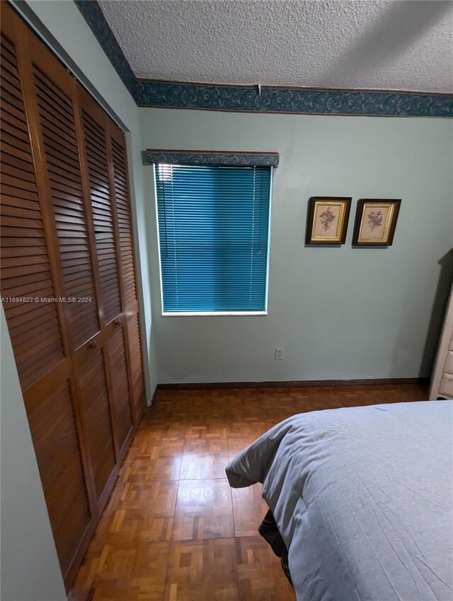 bedroom featuring parquet floors, a textured ceiling, and a closet