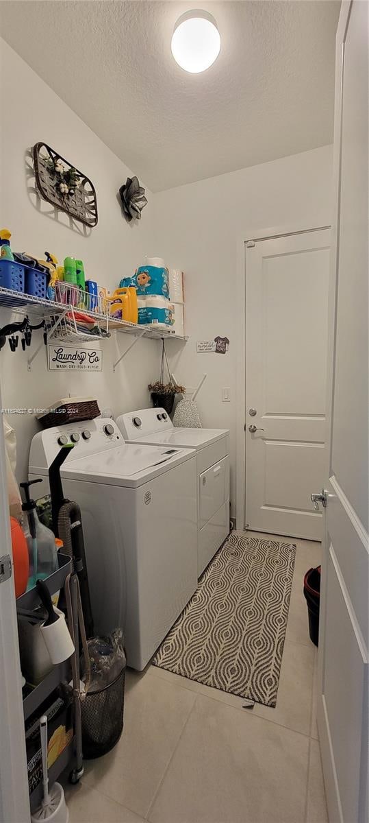 washroom featuring light tile patterned floors, a textured ceiling, and washer and clothes dryer