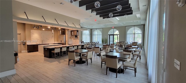 dining room featuring beam ceiling, light wood-type flooring, and coffered ceiling