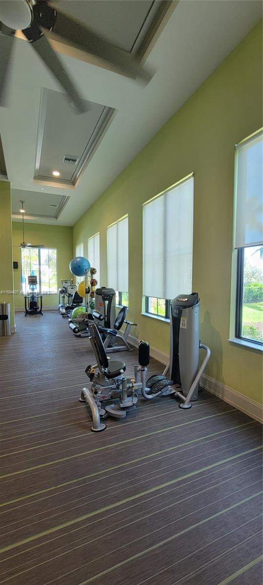 workout area with a tray ceiling and ceiling fan