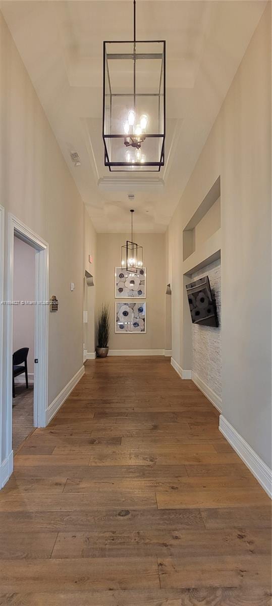 hallway featuring a raised ceiling, a chandelier, and hardwood / wood-style flooring