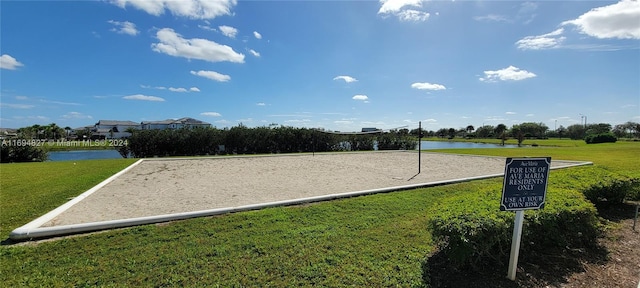 view of home's community with a water view, a yard, and volleyball court