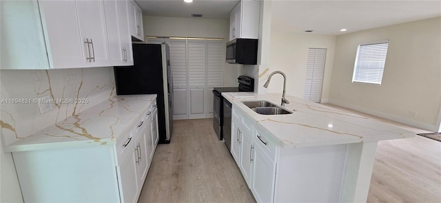 kitchen with light stone countertops, white cabinetry, sink, and stainless steel appliances