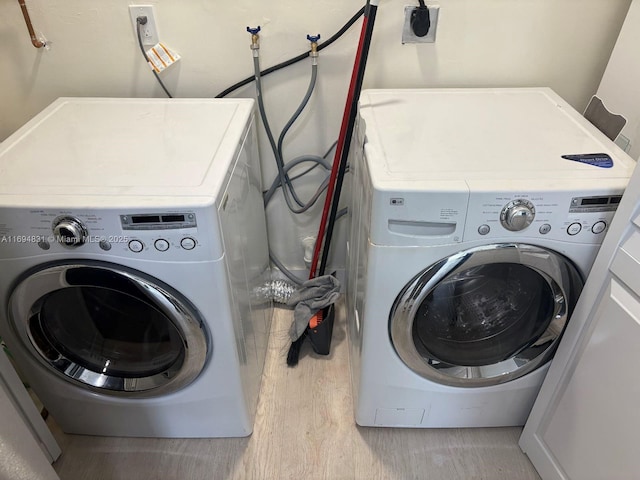 washroom with washing machine and dryer and light hardwood / wood-style floors