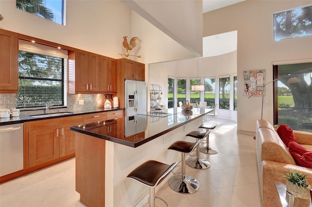 kitchen with a center island, stainless steel appliances, a high ceiling, a kitchen breakfast bar, and tasteful backsplash