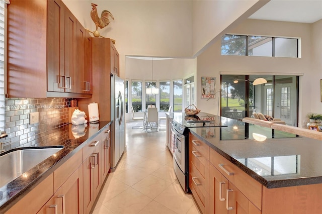 kitchen featuring appliances with stainless steel finishes, plenty of natural light, dark stone countertops, and a high ceiling