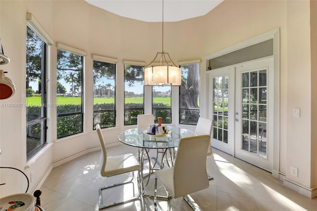 sunroom / solarium with plenty of natural light, a chandelier, and french doors