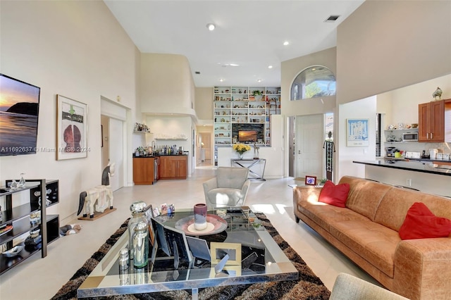 living room with a fireplace and a towering ceiling