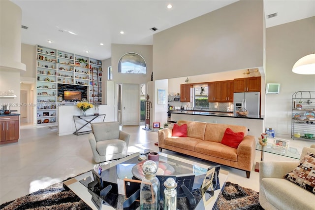 living room with a fireplace, light tile patterned floors, and a towering ceiling