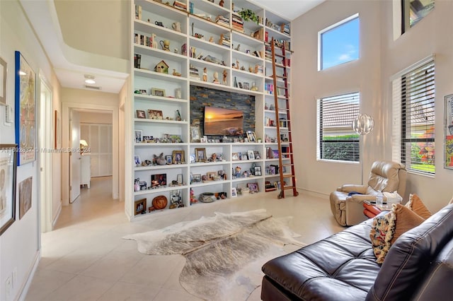 living area with light tile patterned floors, a towering ceiling, and built in features