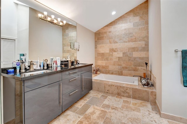 bathroom with vanity, lofted ceiling, and tiled tub