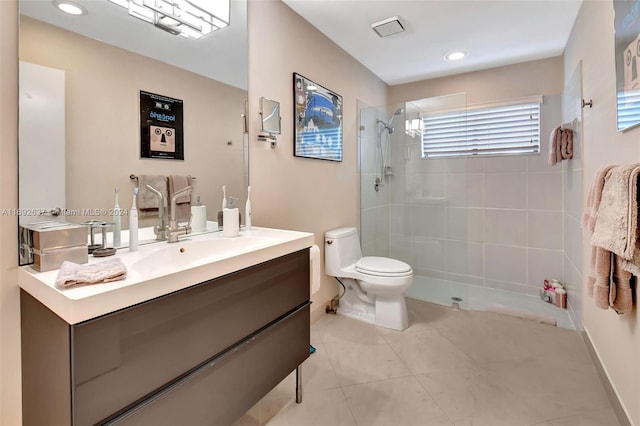 bathroom with tile patterned floors, vanity, toilet, and a tile shower