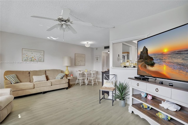 living room with ceiling fan, light hardwood / wood-style floors, and a textured ceiling