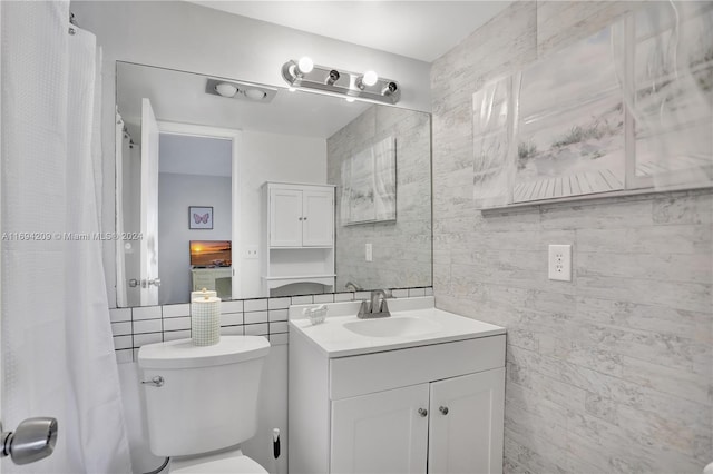 bathroom featuring vanity, tile walls, and toilet