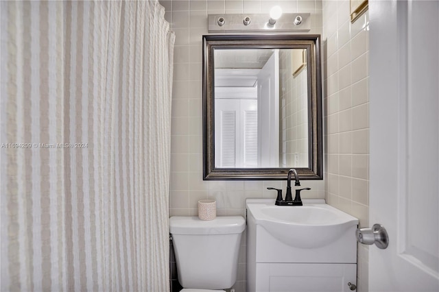 bathroom with vanity, toilet, and tile walls