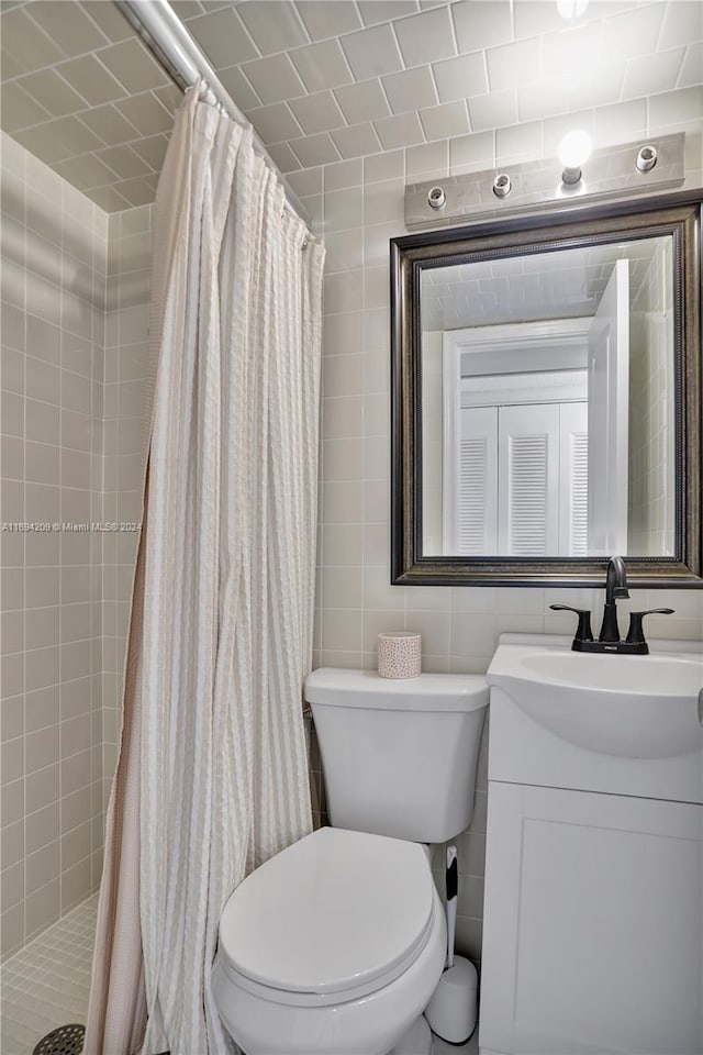 bathroom with curtained shower, vanity, tile walls, and toilet