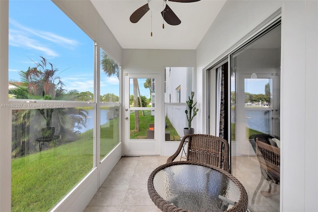 sunroom featuring ceiling fan and a water view