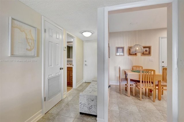 corridor featuring light tile patterned floors and a textured ceiling