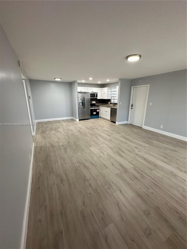 unfurnished living room with light hardwood / wood-style flooring and sink