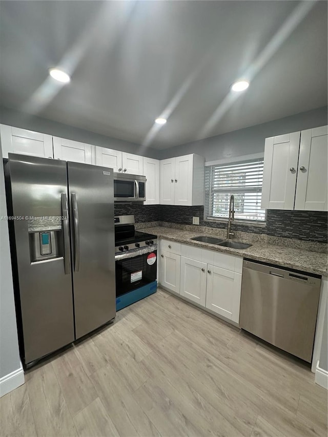 kitchen featuring appliances with stainless steel finishes, light hardwood / wood-style flooring, white cabinetry, and sink