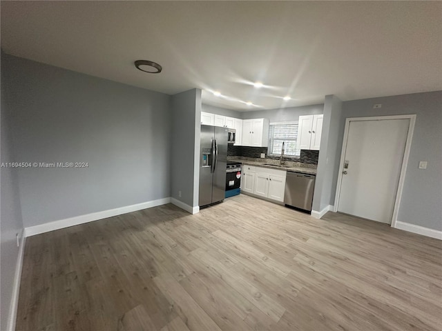 kitchen featuring appliances with stainless steel finishes, tasteful backsplash, sink, light hardwood / wood-style flooring, and white cabinetry