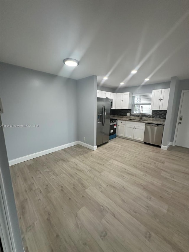 kitchen with backsplash, stainless steel appliances, sink, light hardwood / wood-style floors, and white cabinetry