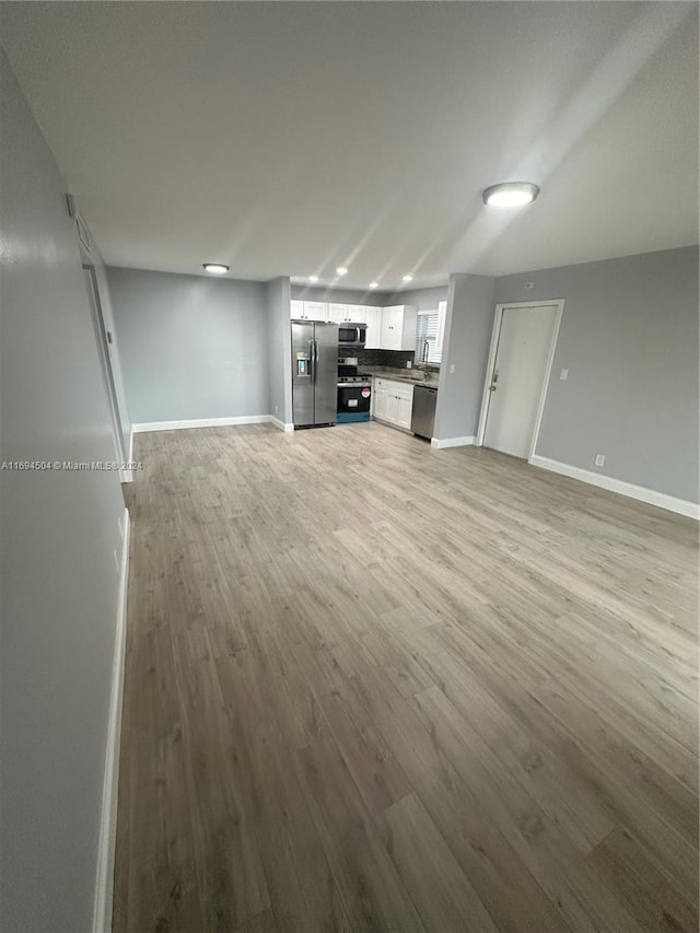 unfurnished living room with light wood-type flooring and sink