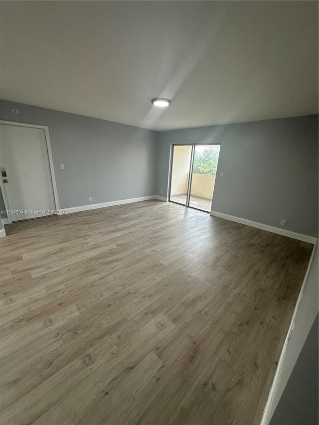 spare room with light hardwood / wood-style flooring and lofted ceiling