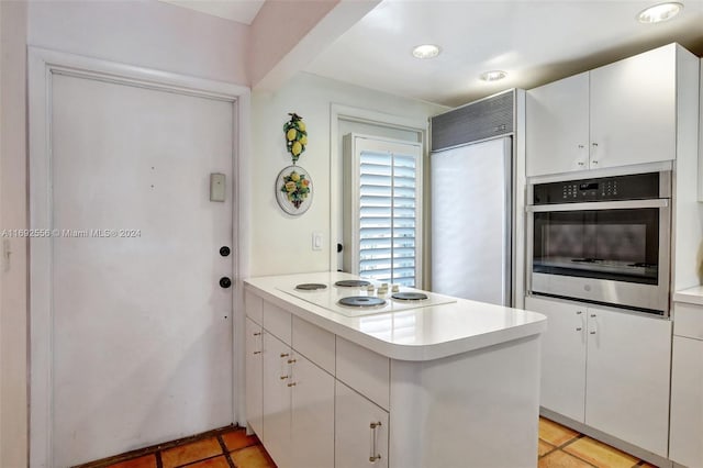 kitchen featuring white cabinets, oven, paneled built in refrigerator, and kitchen peninsula