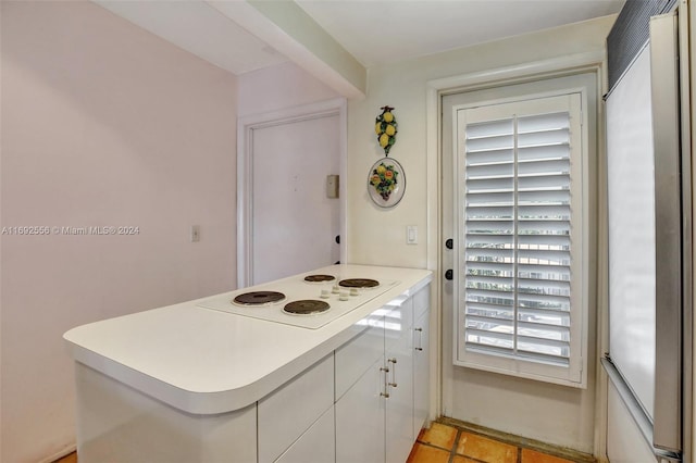 kitchen featuring kitchen peninsula, white electric cooktop, white cabinets, and stainless steel built in refrigerator