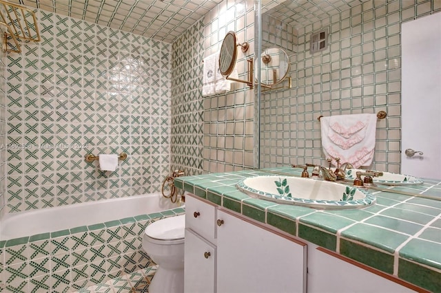 bathroom featuring a washtub, vanity, toilet, and tile walls