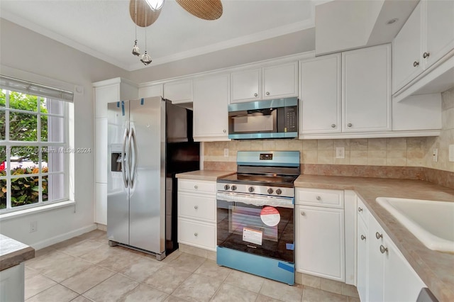 kitchen featuring tasteful backsplash, ornamental molding, stainless steel appliances, ceiling fan, and white cabinets