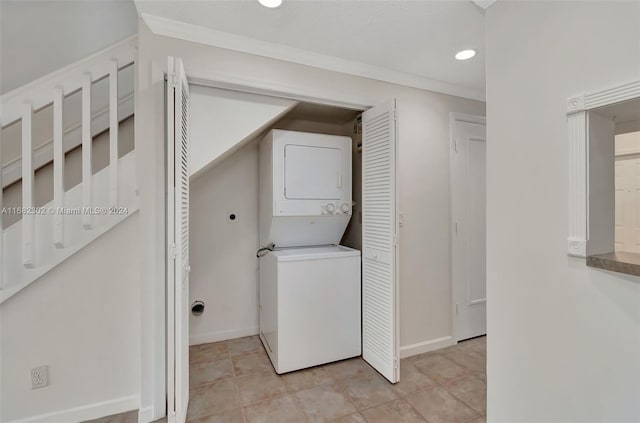 washroom featuring crown molding, stacked washer and dryer, and light tile patterned flooring