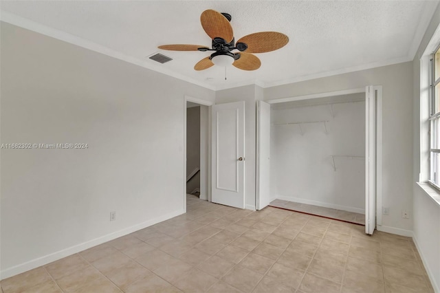 unfurnished bedroom featuring ceiling fan, a closet, crown molding, and a textured ceiling