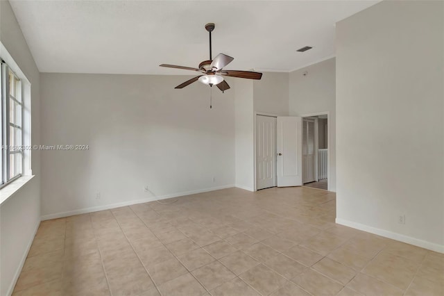 tiled spare room with ceiling fan and high vaulted ceiling