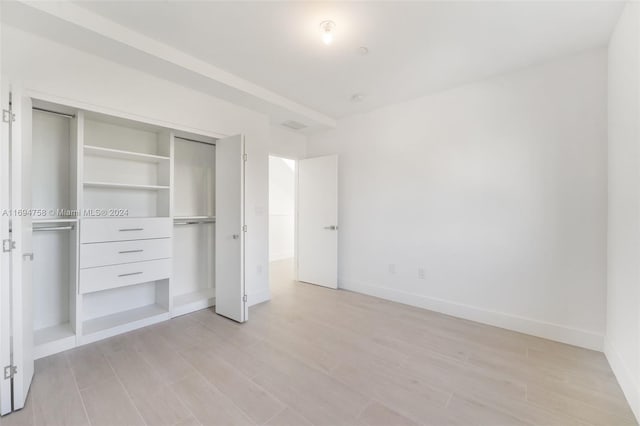 unfurnished bedroom with light hardwood / wood-style floors and a closet