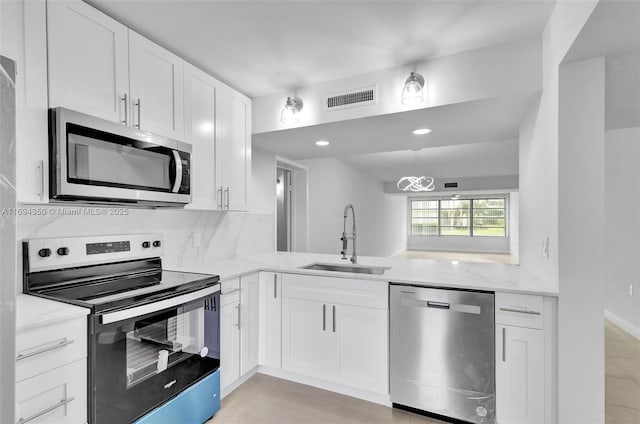 kitchen with appliances with stainless steel finishes, light stone countertops, sink, and white cabinets