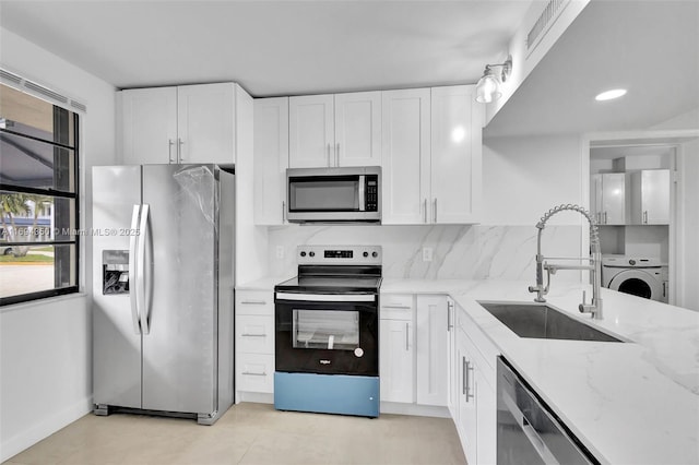 kitchen with washer / clothes dryer, sink, white cabinets, light stone counters, and stainless steel appliances