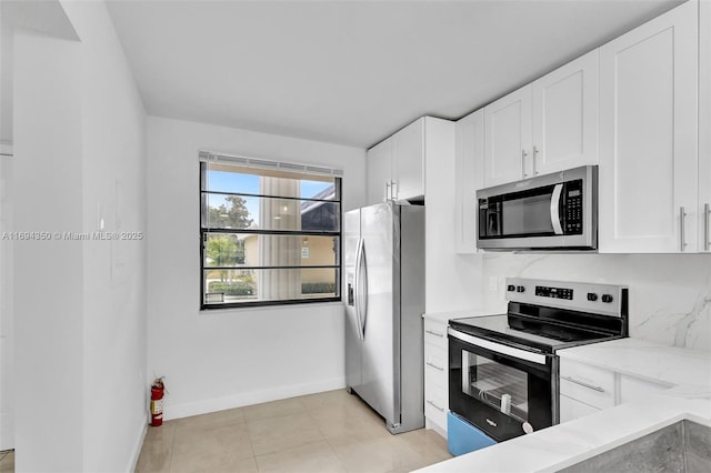 kitchen featuring light stone countertops, white cabinets, appliances with stainless steel finishes, and light tile patterned floors