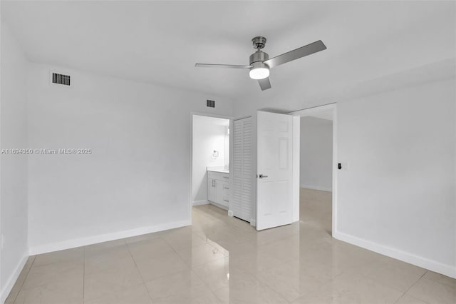 unfurnished bedroom with ceiling fan, a closet, and ensuite bath