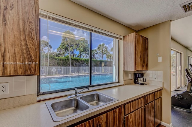 kitchen featuring backsplash, sink, and a textured ceiling