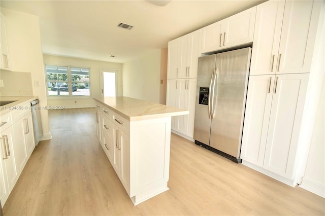 kitchen with a center island, white cabinetry, stainless steel appliances, and light hardwood / wood-style flooring