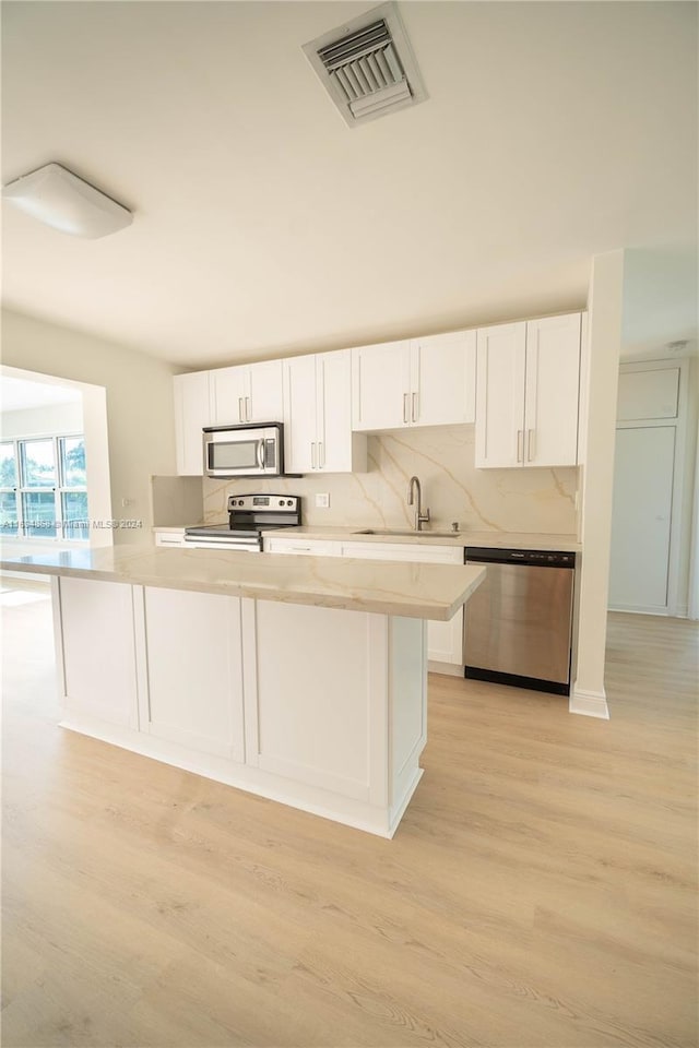 4450 SW 34th Dr, Dania Beach, FL 33312 - kitchen with appliances with stainless steel finishes, white cabinets, light countertops, light wood finished floors, and a sink