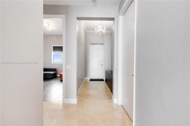 hall with light tile patterned flooring, ornamental molding, and a notable chandelier