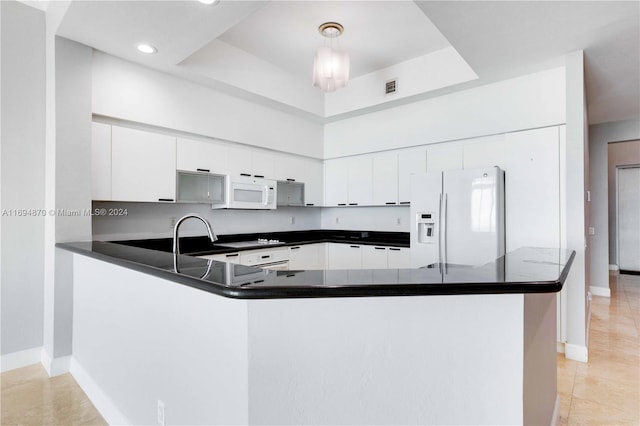 kitchen featuring kitchen peninsula, white appliances, white cabinets, and hanging light fixtures