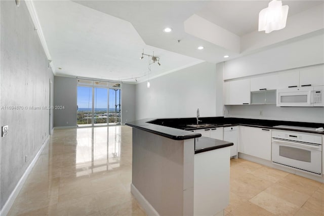 kitchen featuring kitchen peninsula, white appliances, sink, pendant lighting, and white cabinets