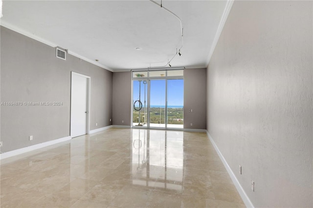 empty room featuring expansive windows and crown molding